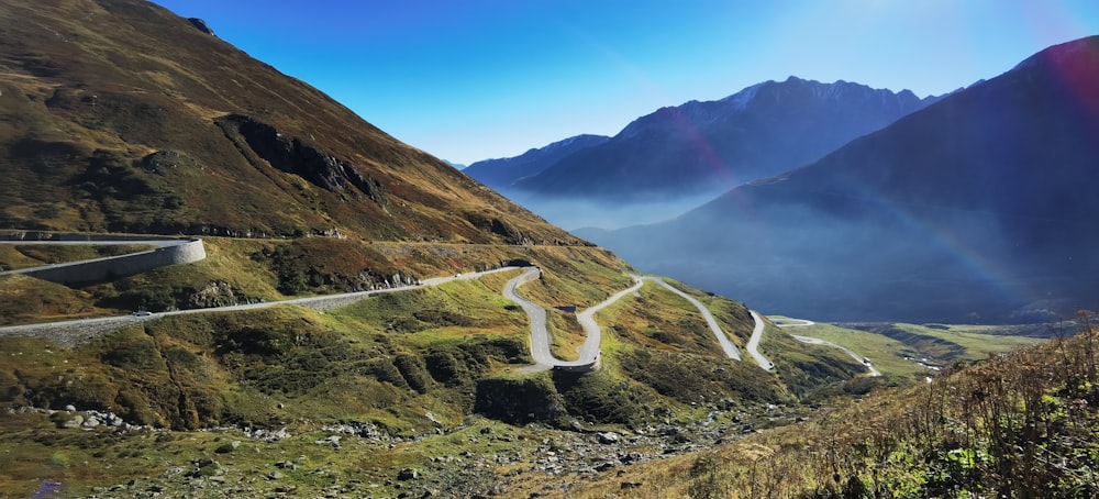 a winding road in the mountains with a rainbow in the sky