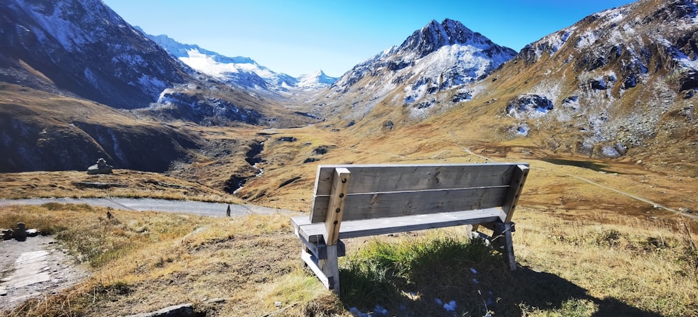 un banc en bois posé au sommet d’une colline couverte d’herbe