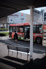 A colorful city bus stopping at a busy urban bus stop with passengers boarding.