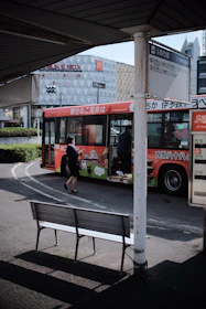 A colorful city bus stopping at a busy urban bus stop with passengers boarding.