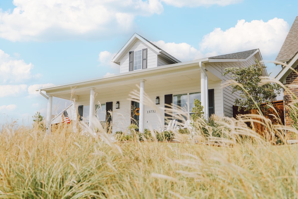 a house in a field with tall grass in front of it