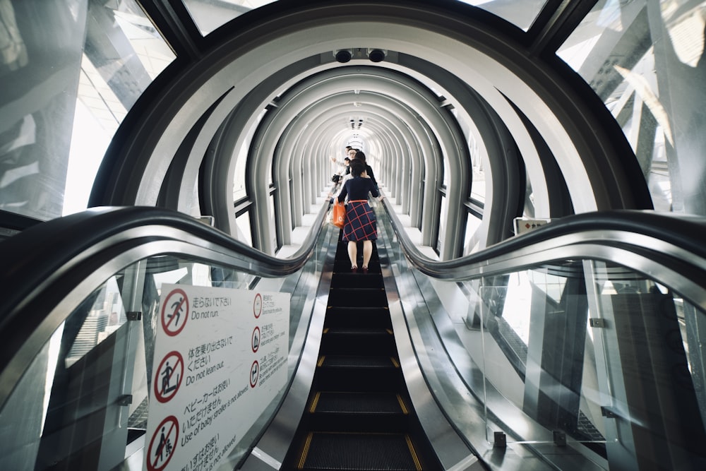 a woman walking down an escalator in a building