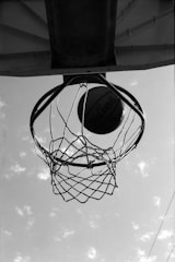 a black and white photo of a basketball going through the hoop