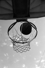 a black and white photo of a basketball going through the hoop