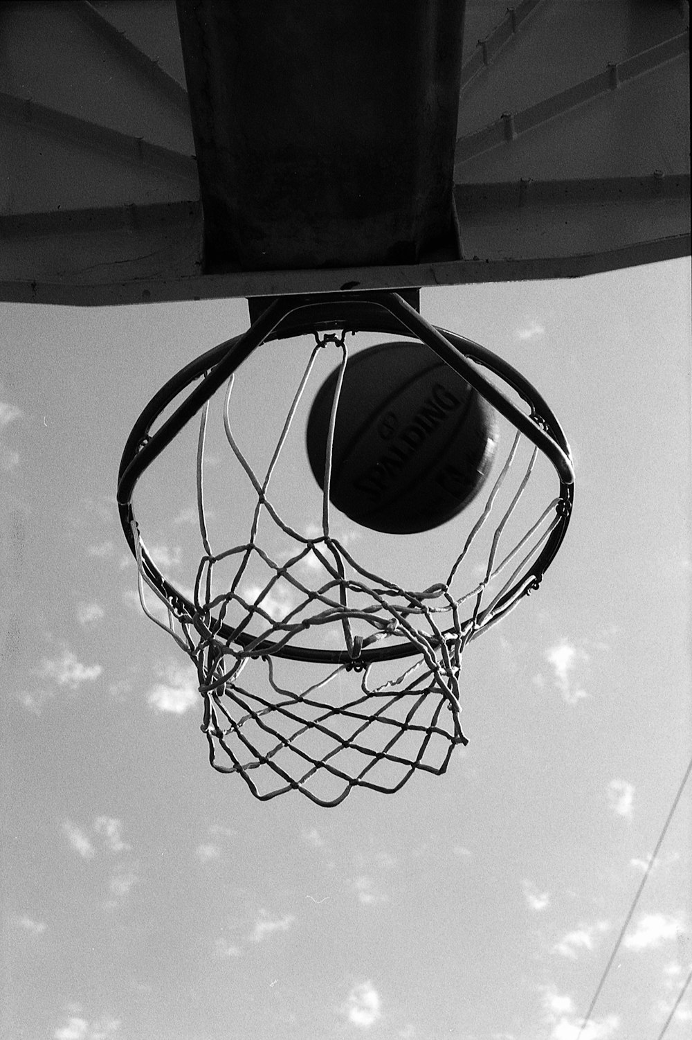 a black and white photo of a basketball going through the hoop