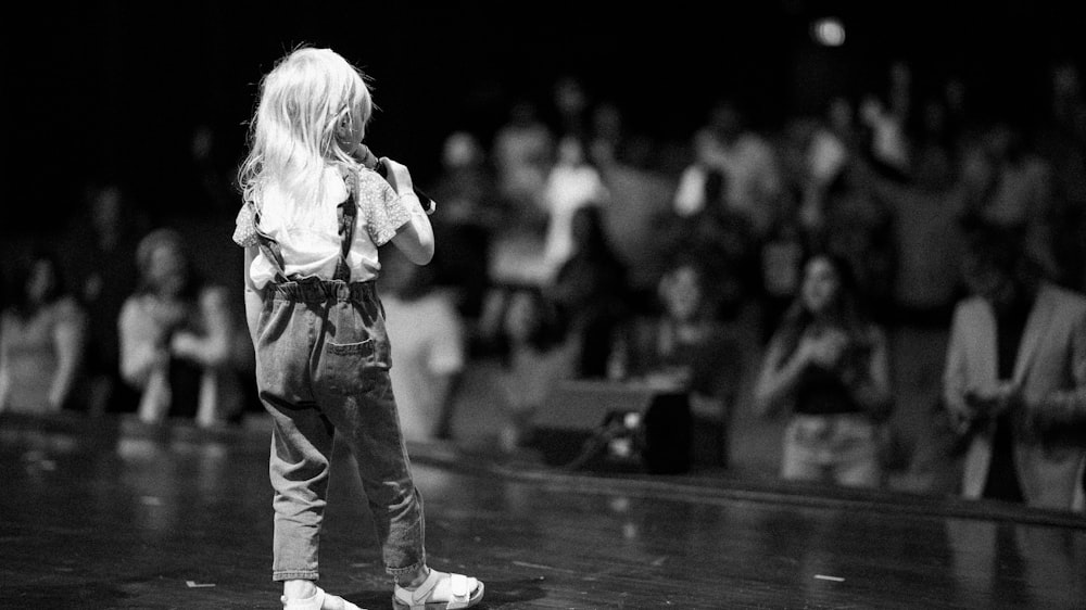 a little girl standing in front of a crowd of people