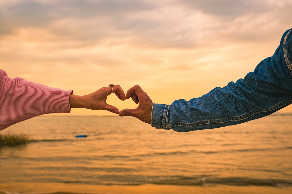 two people making a heart shape with their hands