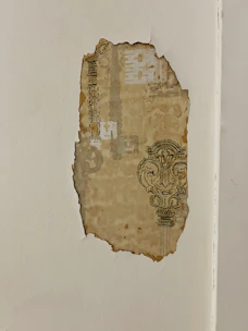A close-up of hands carefully removing old wallpaper to prepare a wall for a fresh finish.