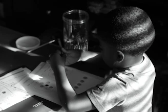 A young pre-teen thoughtfully filling out an emotional wellness workbook at a sunny desk.