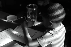 A young pre-teen thoughtfully filling out an emotional wellness workbook at a sunny desk.