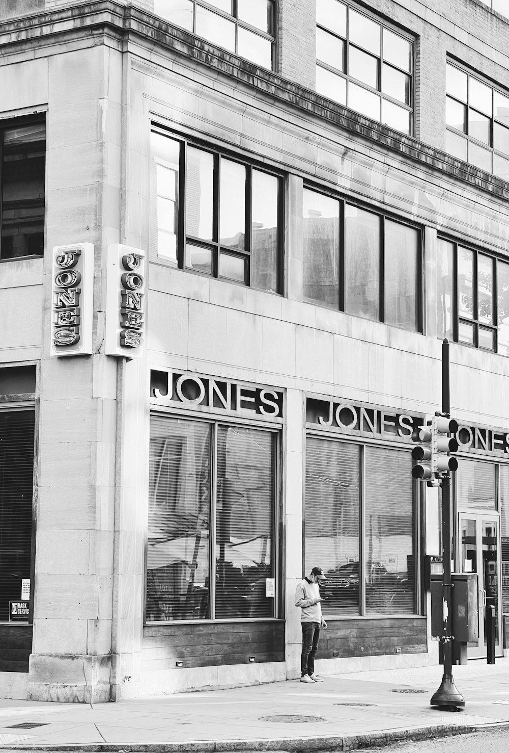 uma foto em preto e branco de um homem em pé na frente de uma loja jones jones