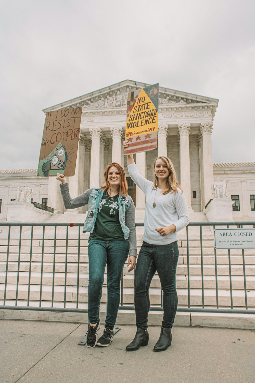 two women holding signs in front of the supreme building
