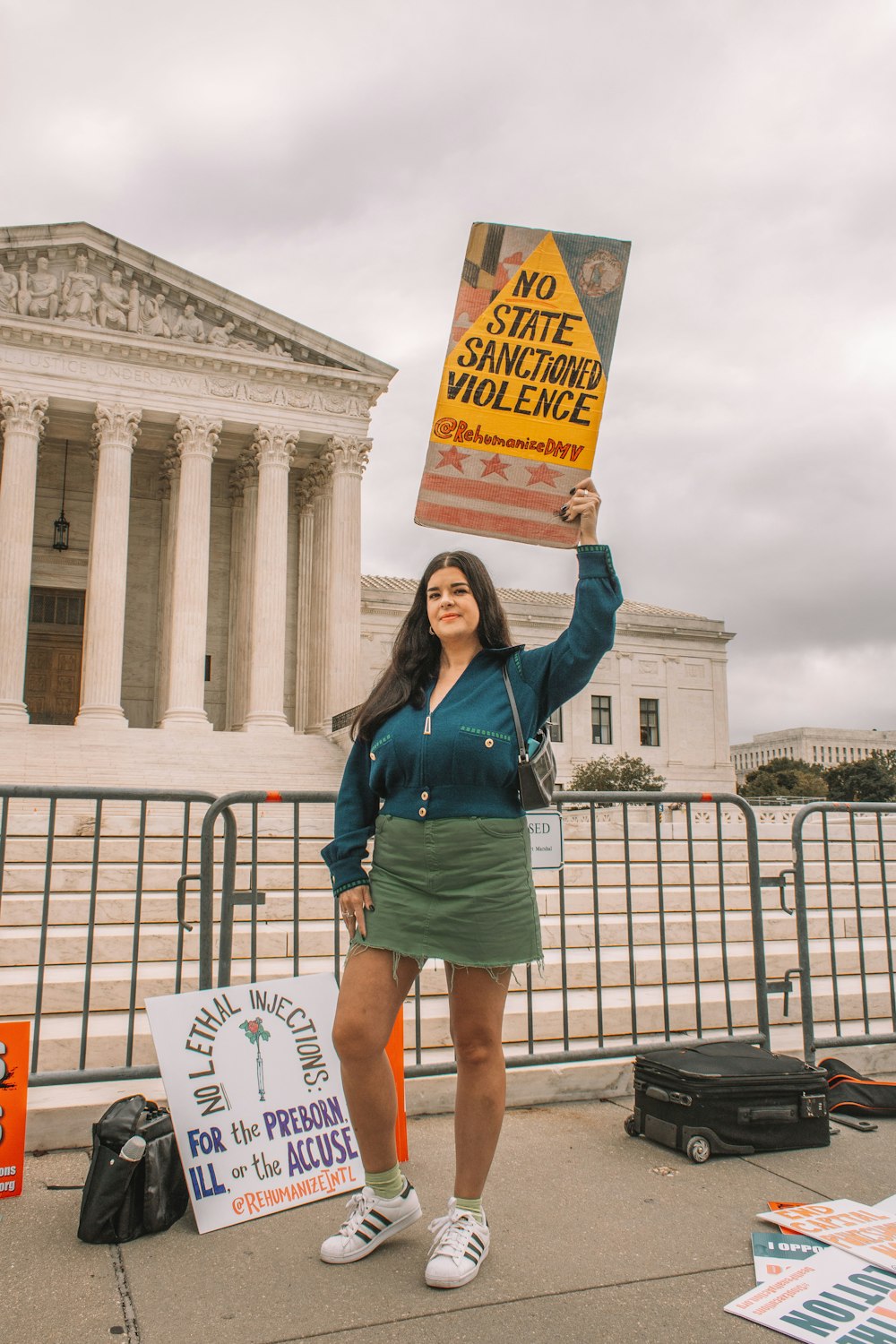 Una mujer sosteniendo un cartel frente al Edificio Supremo