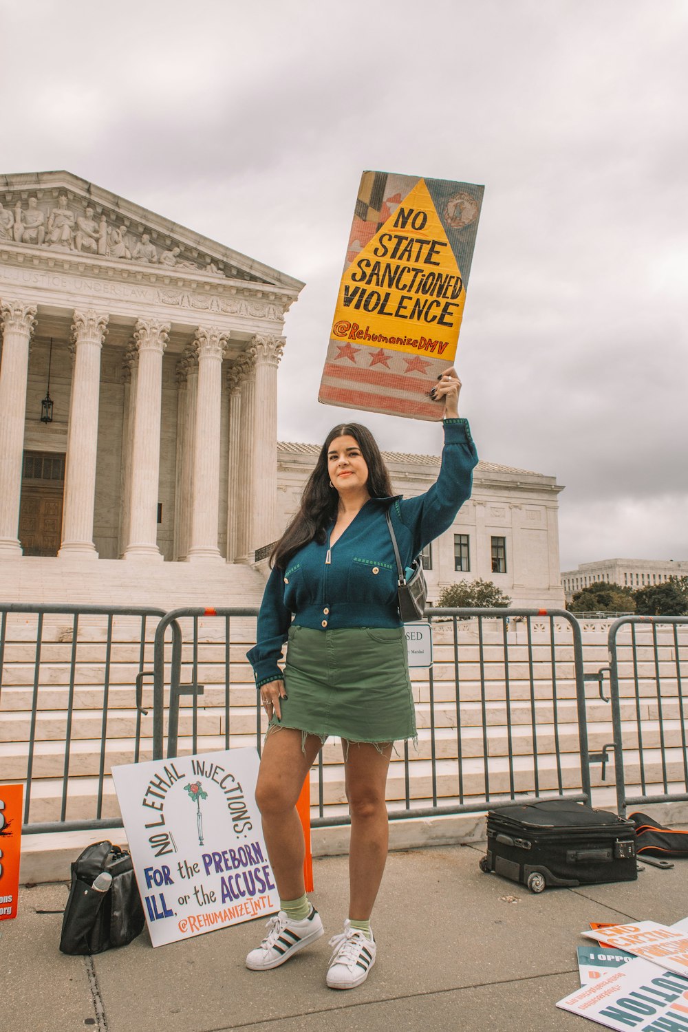 a woman holding a sign in front of the supreme building