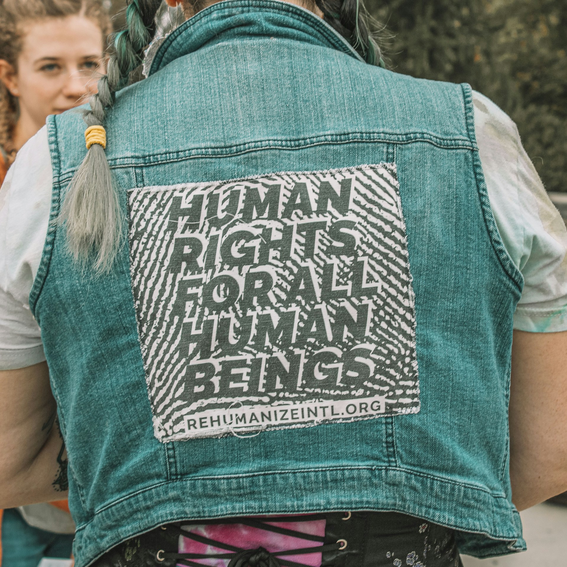 a woman wearing a denim vest with a human rights message on it