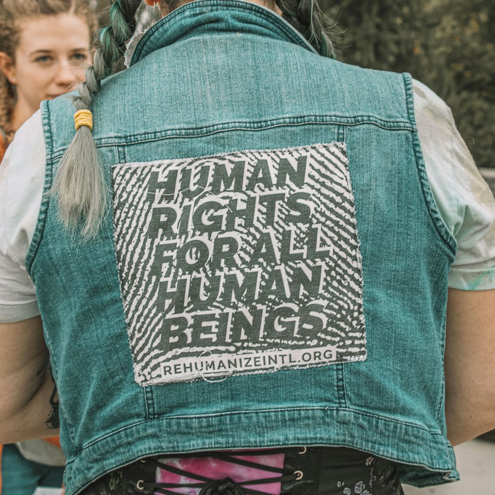 a woman wearing a denim vest with a human rights message on it