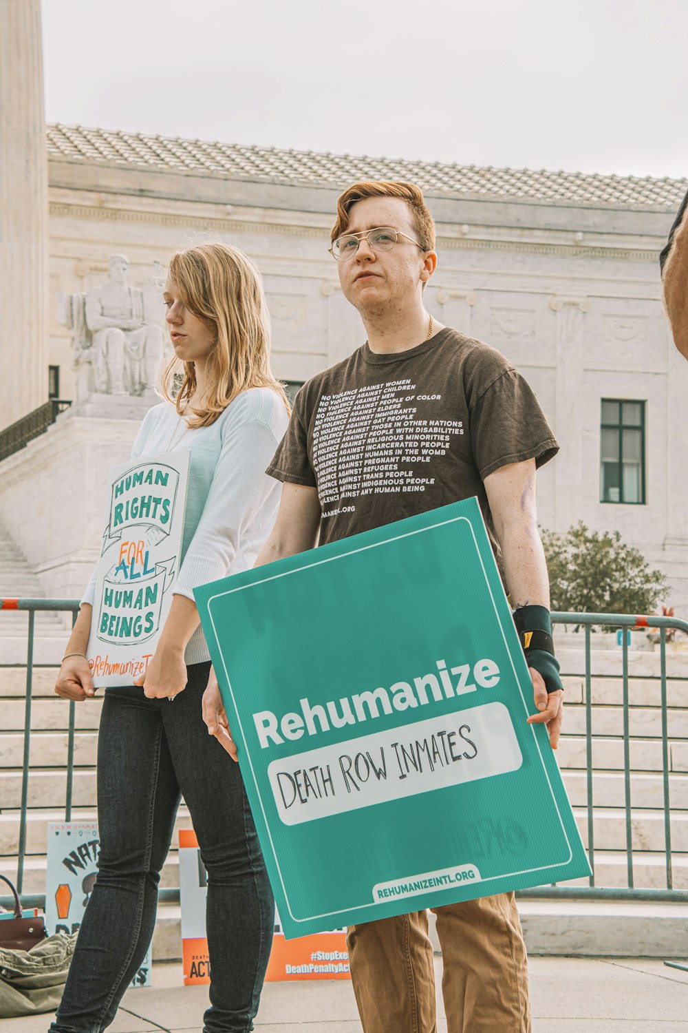 a man and a woman holding a sign in front of a building