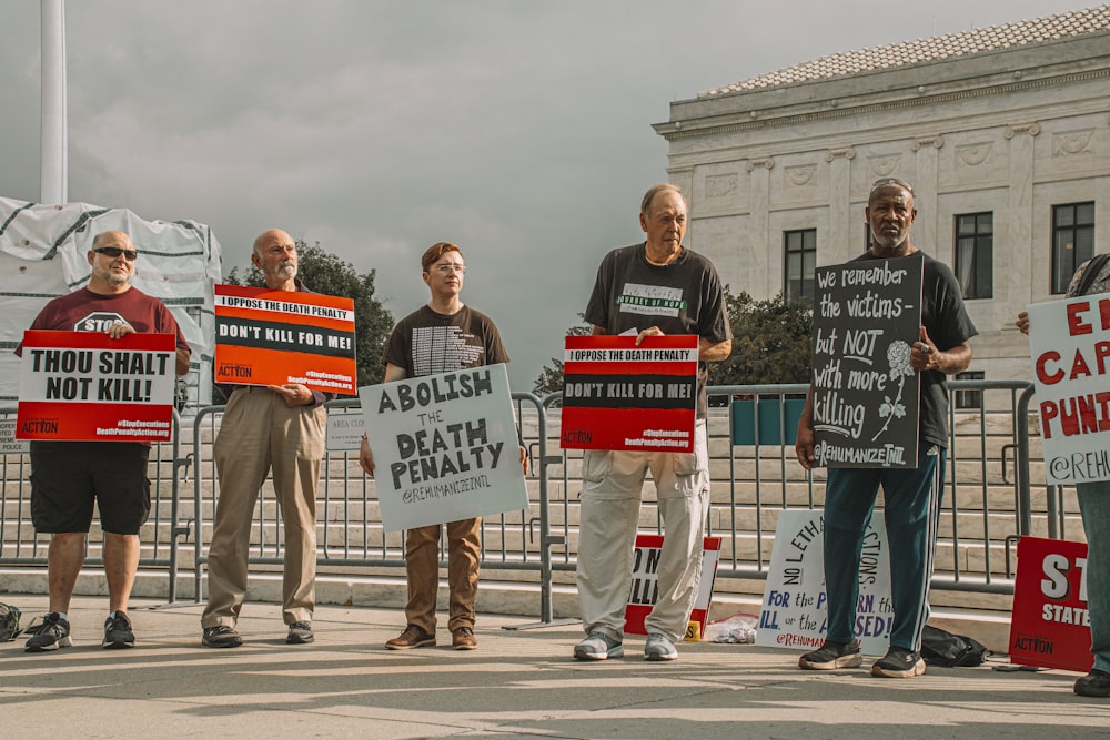 a group of people holding signs in front of a fence