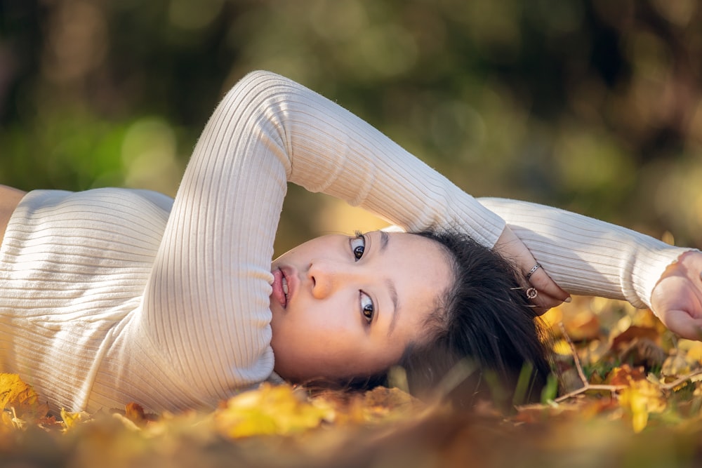 a woman laying on the ground in a field of leaves