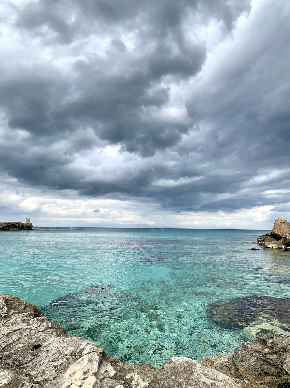 a body of water surrounded by rocks under a cloudy sky