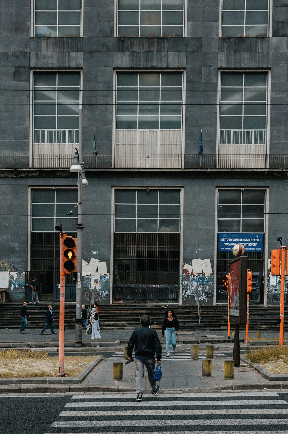 a group of people walking across a street next to a tall building