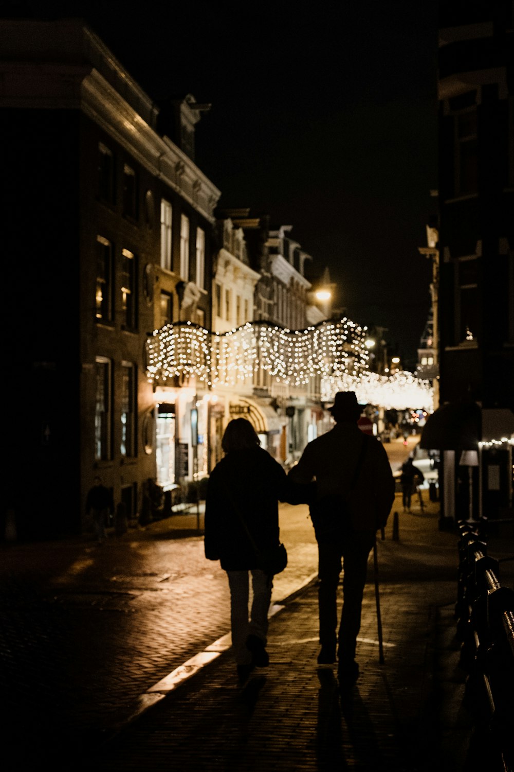 a couple of people walking down a street at night