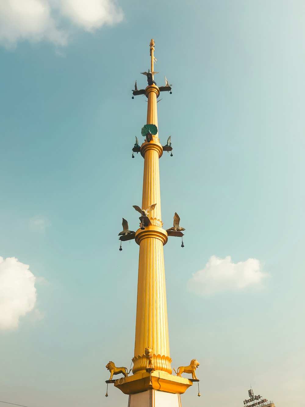 a tall yellow tower with birds flying around it