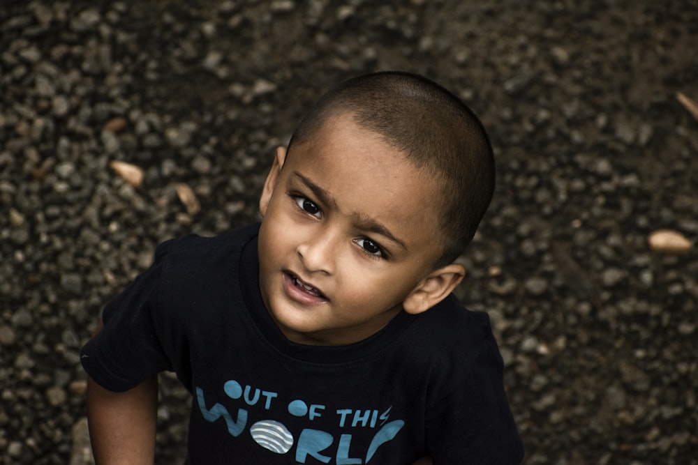 a young boy with a shaved head and a t - shirt that says out of