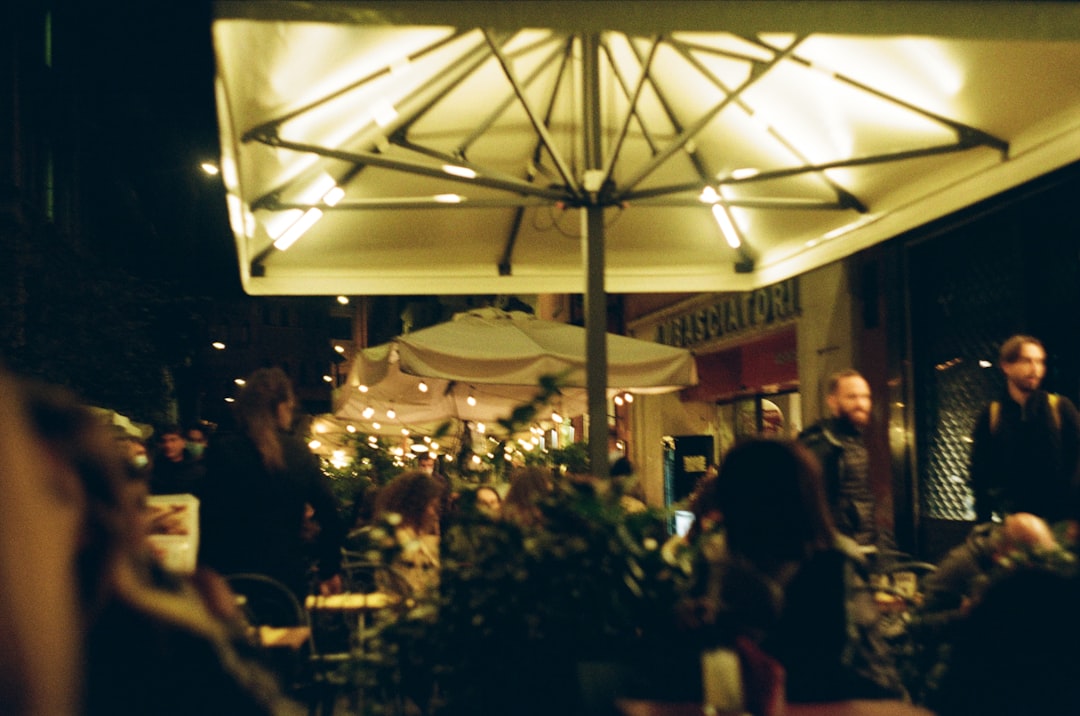 a group of people sitting at tables under an umbrella,
