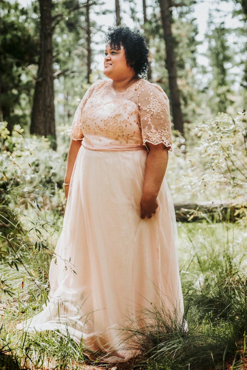 a woman in a dress standing in the woods