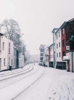 a snowy street with buildings and a street light