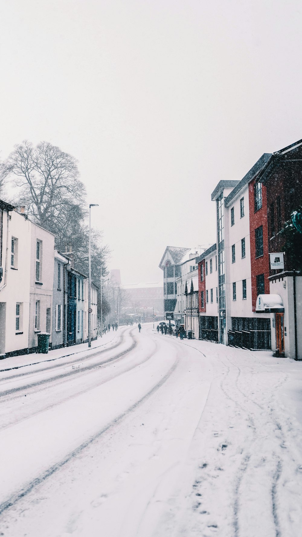 a snowy street with buildings and a street light