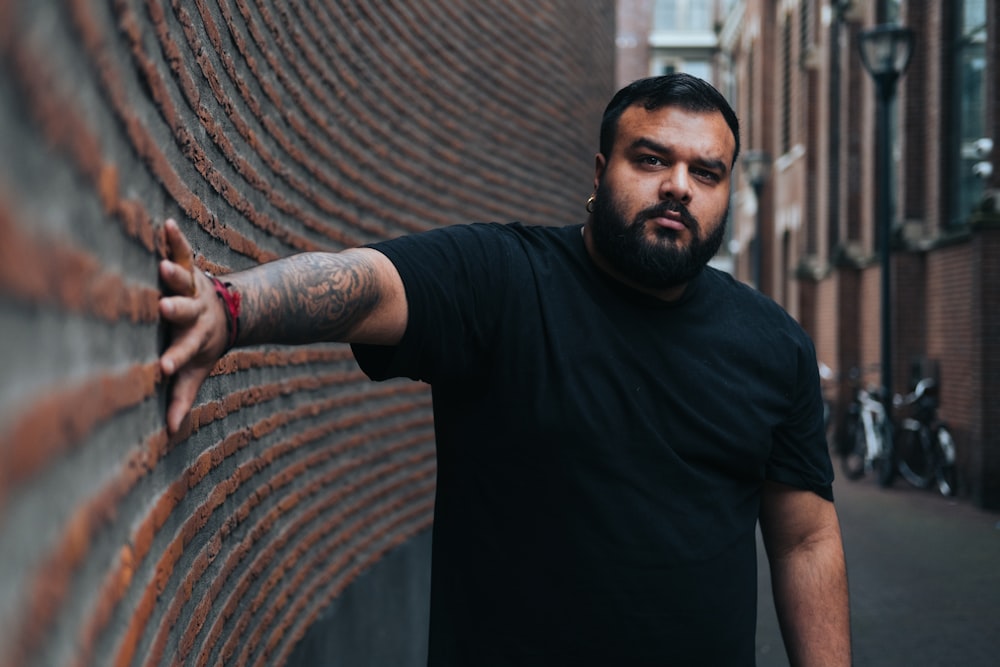 a man leaning against a brick wall with his hands on the wall