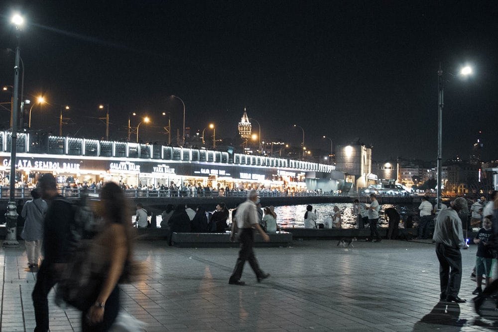 a group of people walking across a street at night