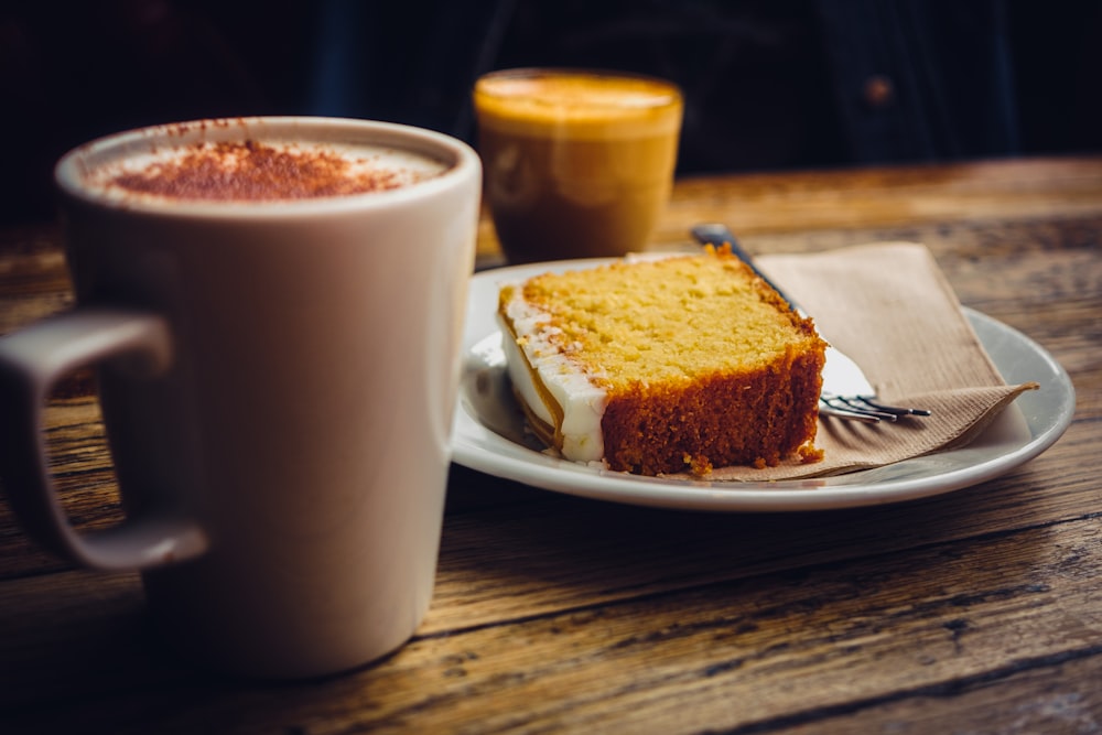 a piece of cake on a plate next to a cup of coffee