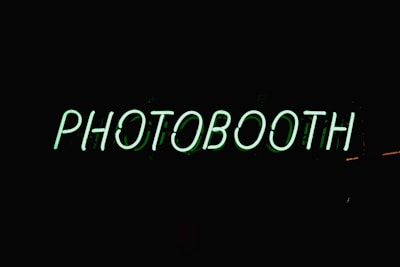 a neon sign that reads photo booth on a dark background