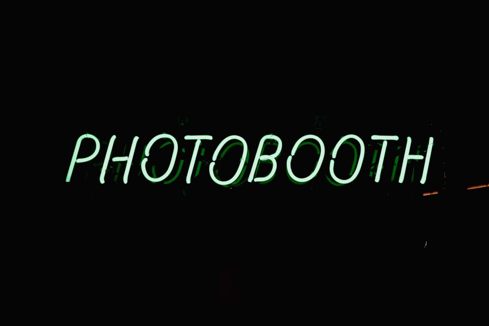 a neon sign that reads photo booth on a dark background