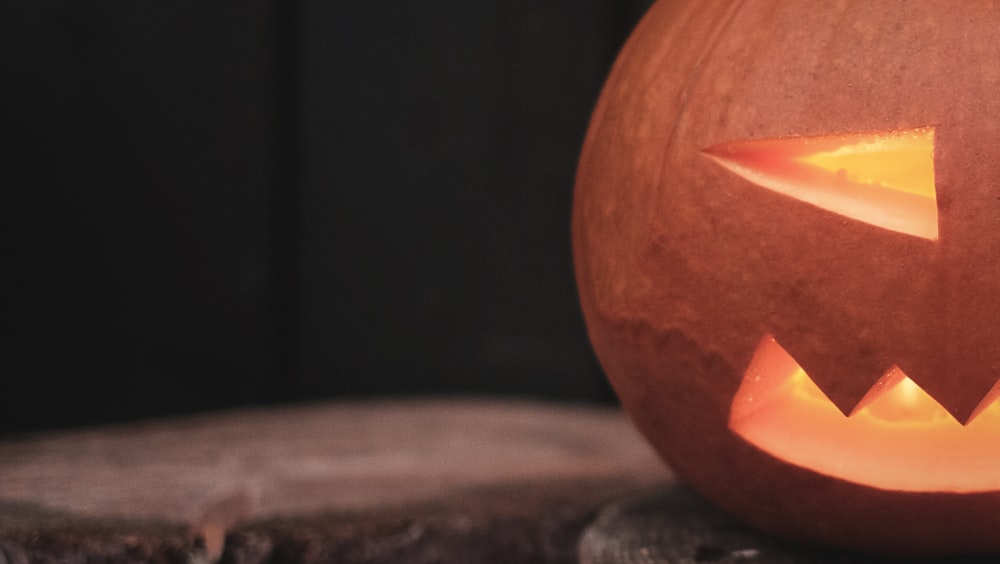 a carved pumpkin sitting on top of a tree stump