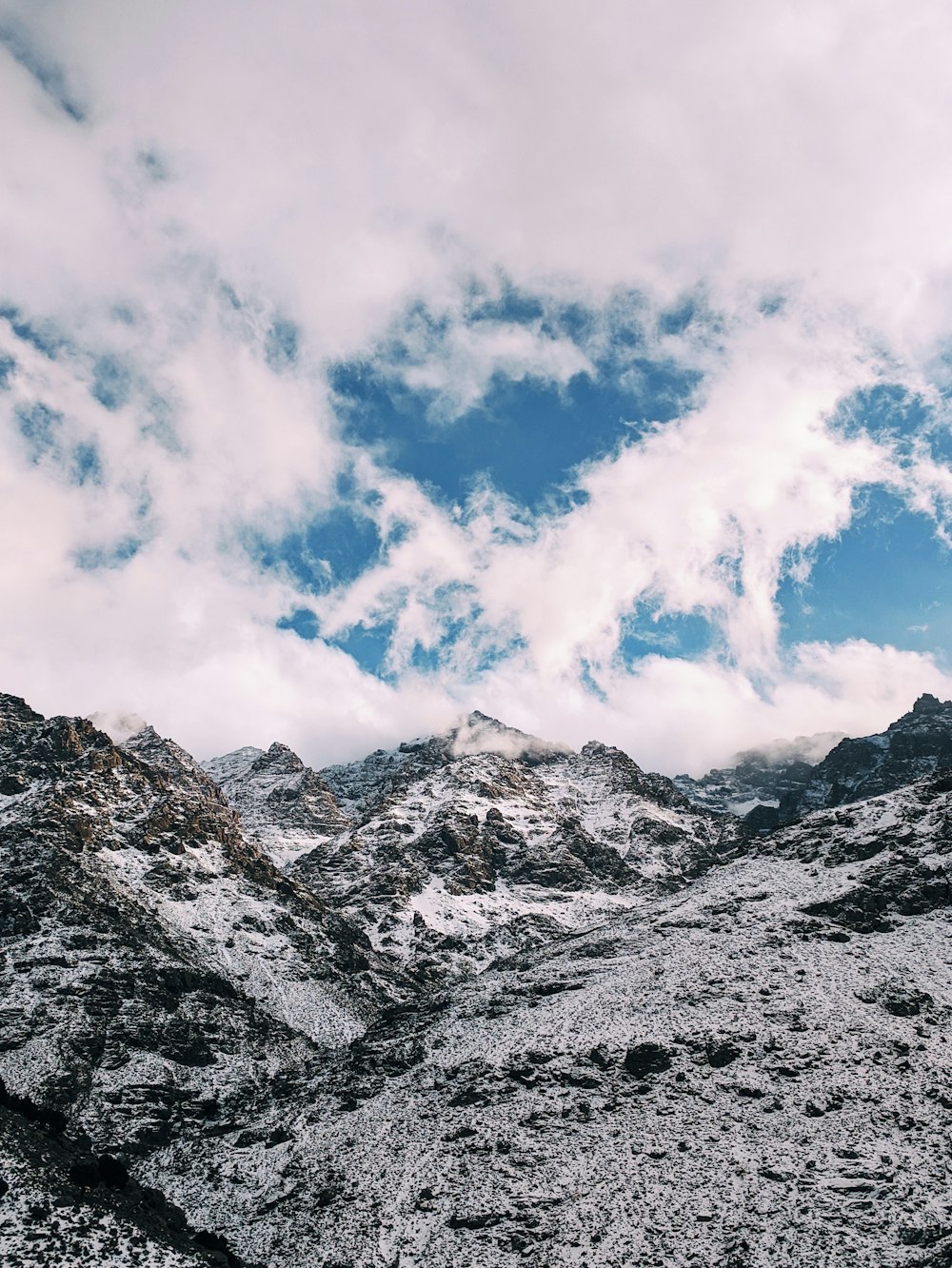 a snow covered mountain under a cloudy blue sky