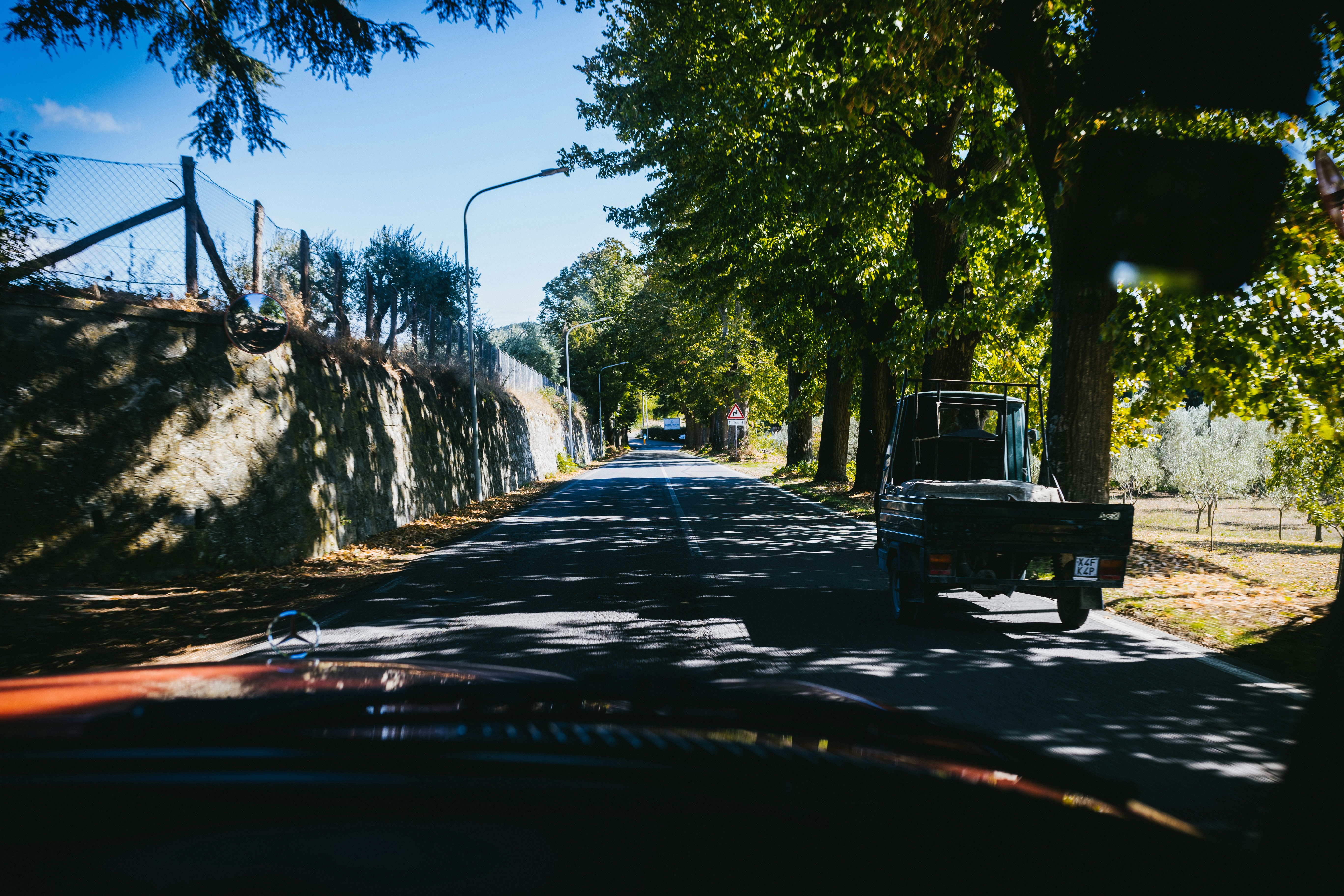 a truck driving down a street next to a forest