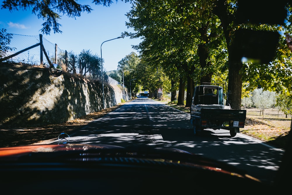 a truck driving down a street next to a forest