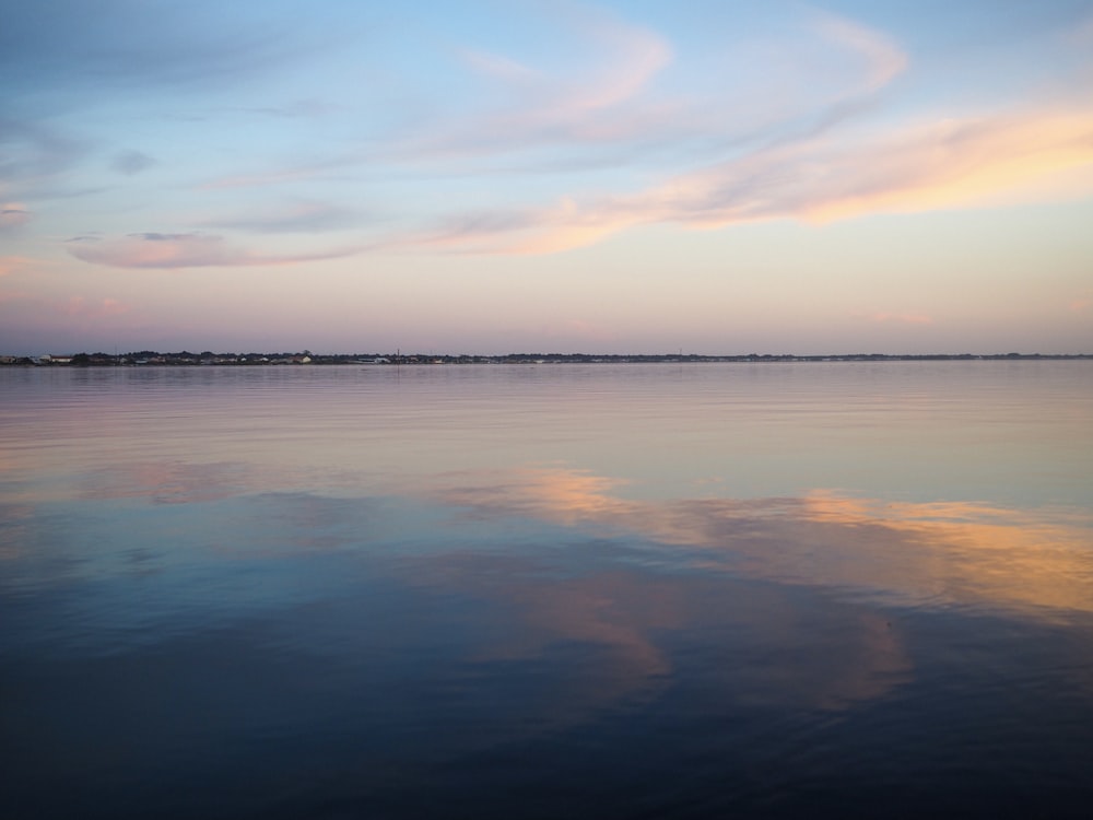 a large body of water with a sky in the background