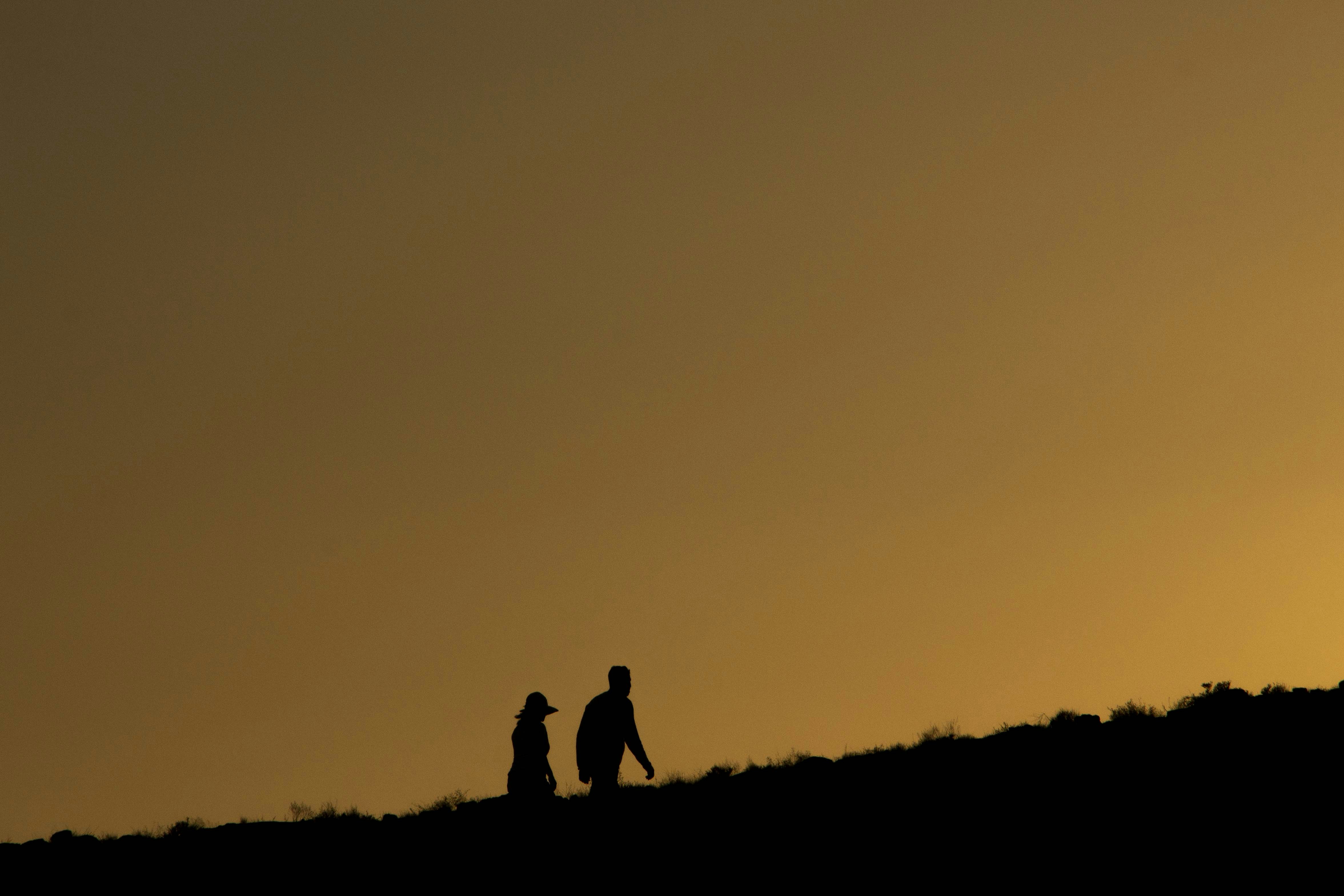 Eine Silhouette einer Mutter und eines Sohnes, die sich an den Händen halten und in den Sonnenuntergang gehen