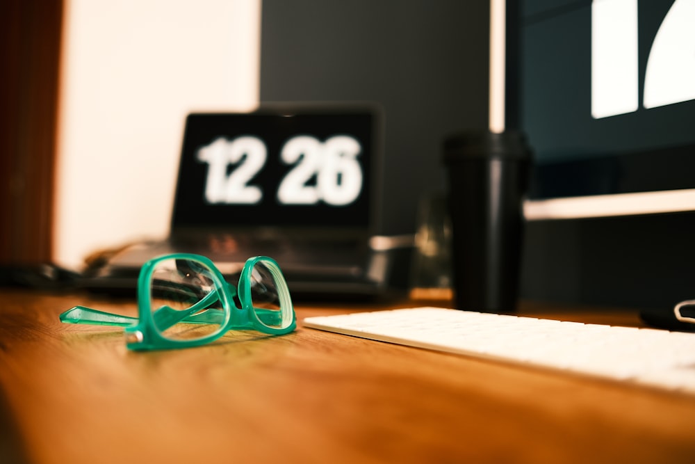 a pair of green glasses sitting on top of a wooden desk