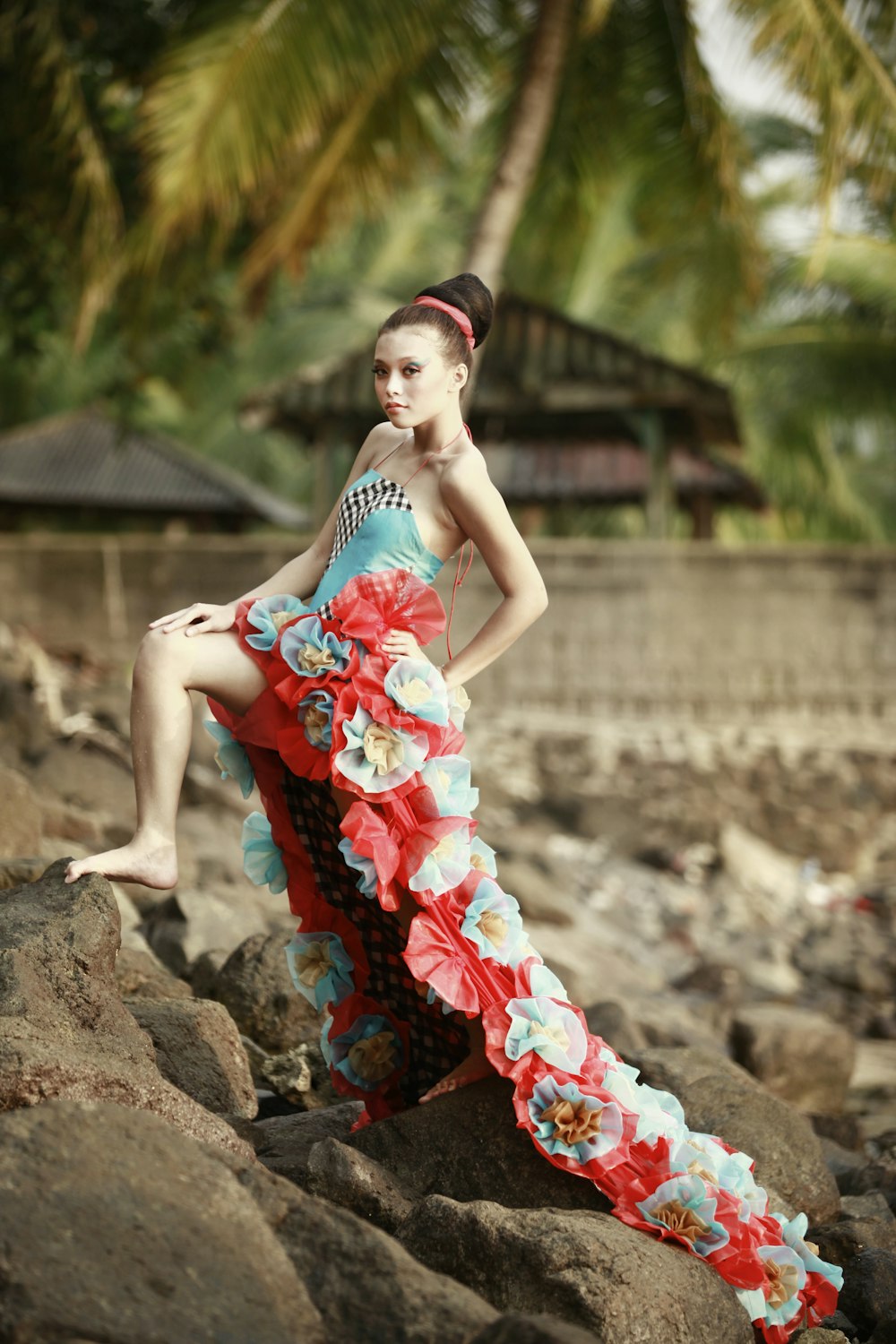a woman in a colorful dress sitting on a rock