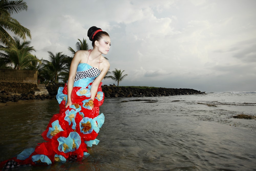 a woman in a red and blue dress standing in the water