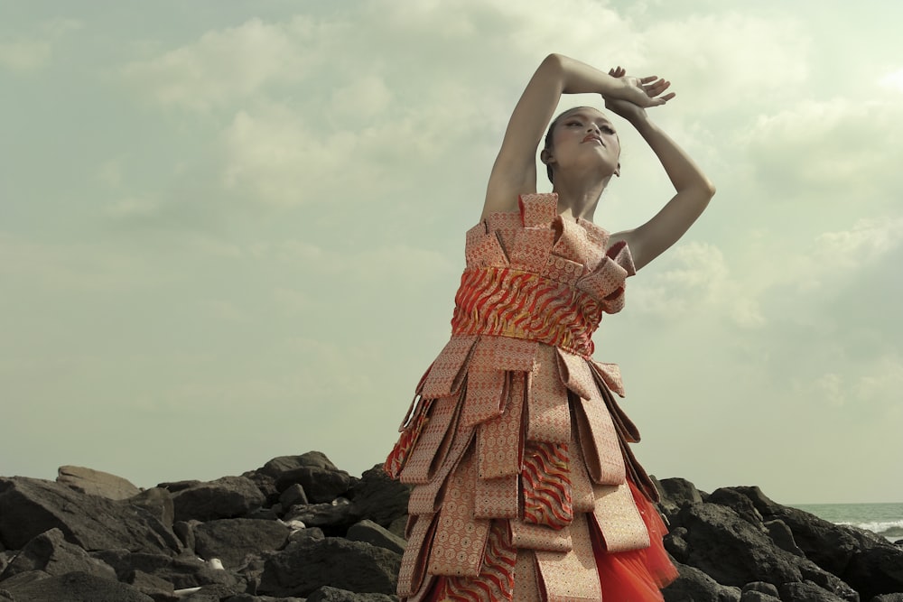 a woman in a dress standing on rocks near the ocean