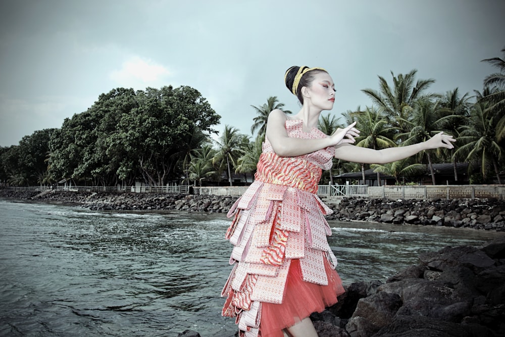 a woman in a dress standing on rocks near the water