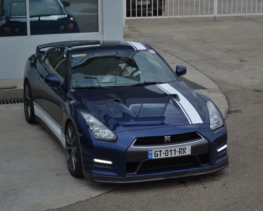 a blue sports car parked in front of a building