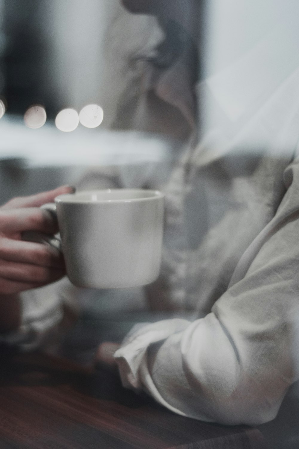 a person sitting at a table with a coffee cup